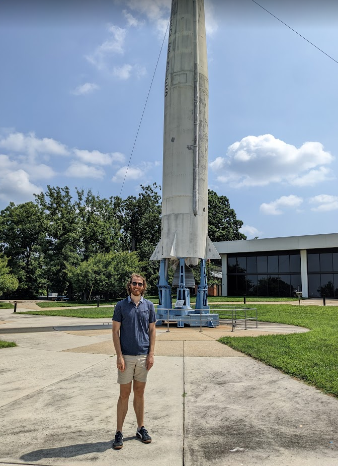 A photograph of a man standing in front of a rocket at NASA Goddard Space Flight Center